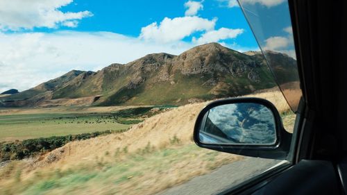 Reflection of mountains in side-view mirror