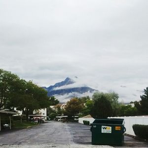 Road amidst trees against cloudy sky