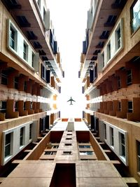 Directly below shot of airplane flying over buildings against sky