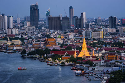 Boats in river amidst buildings in city against sky