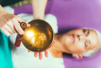 Cropped hands of woman playing singing bowl for customer in spa