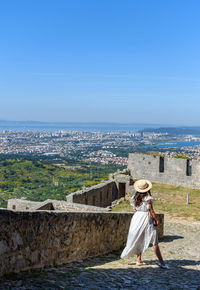 Young woman in white dress standing at klis fortress overlooking coastal city of split in croatia