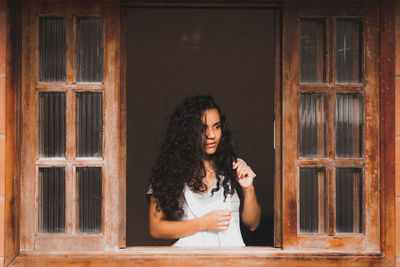Portrait of woman standing against window
