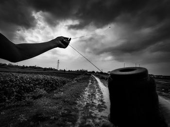 Person holding umbrella on field against sky