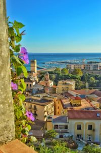 Buildings by sea against clear blue sky