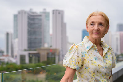 Portrait of smiling woman standing against city in background