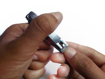 Close-up of hand holding cigarette over white background