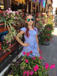 Woman wearing sunglasses standing by flower pot