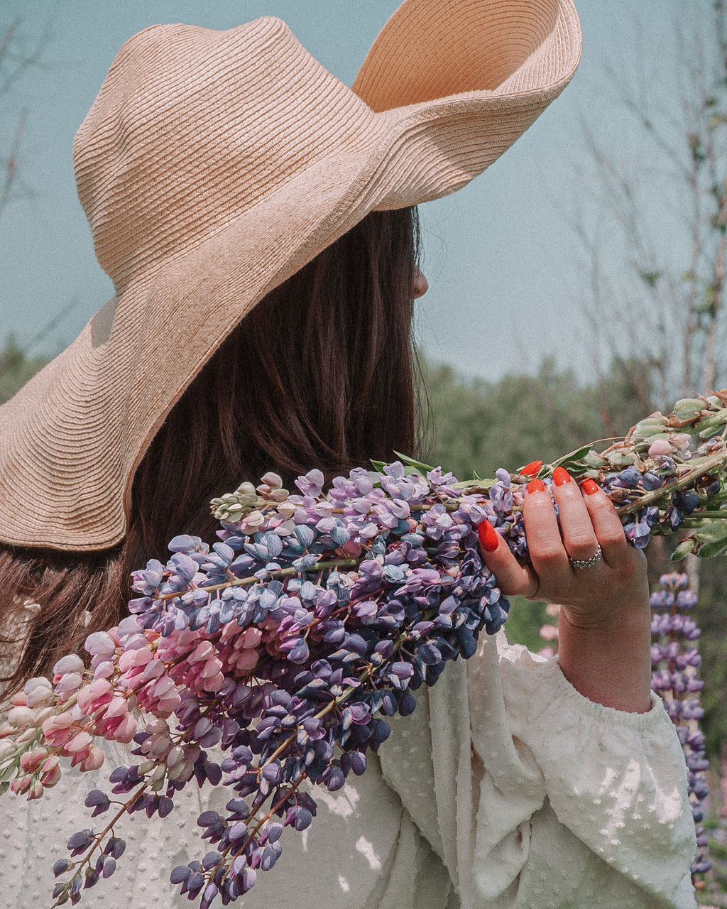 one person, women, spring, adult, clothing, fashion accessory, hat, art, flower, nature, plant, straw hat, lifestyles, day, female, hairstyle, leisure activity, flowering plant, long hair, outdoors, rear view, holding, sun hat, agriculture, waist up, portrait, headshot, young adult
