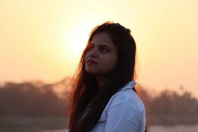 Portrait of young woman against orange sky