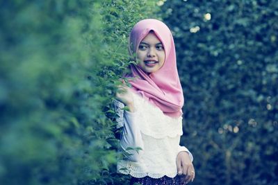 Portrait of smiling young woman standing on tree