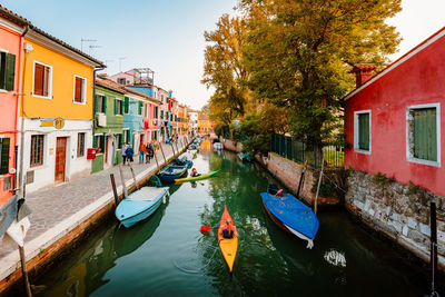 Characteristic burano street with canal and canoes of tourists and colorful houses at sunset