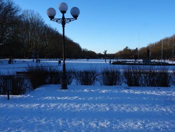 Snow covered street amidst field against sky