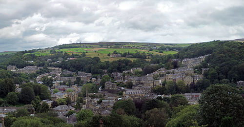 Wide panoramic view of the town of hebden bridge with streets surrounded by trees and pennine fields