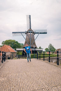 Full length of mid adult man standing on footpath against traditional windmill