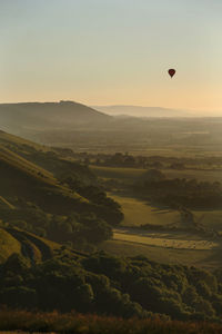 Hot air balloons flying over landscape against sky during sunset