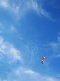 Low angle view of kite with flag flying against blue sky