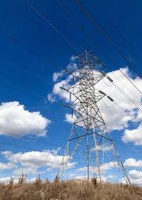 Low angle view of electricity pylon against blue sky