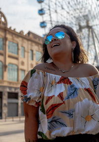 Young woman looking away while standing against built structure