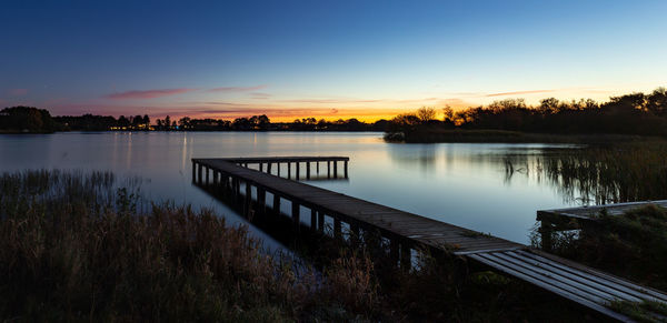 Pier over lake against sky during sunset