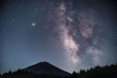 Low angle view of silhouette mountain against star field