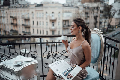 Young woman drinking coffee on railing