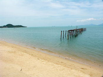 Wooden posts on beach against sky