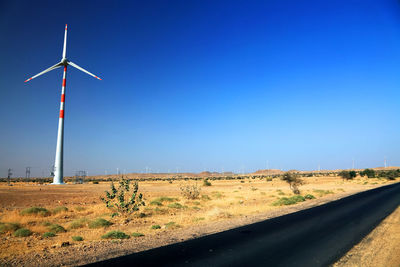Wind turbine at desert against clear blue sky