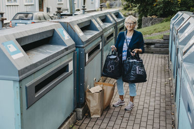 Woman with paper bags at recycling bins