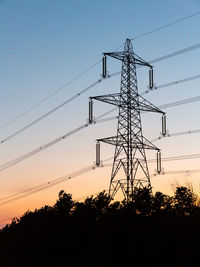 Low angle view of silhouette electricity pylon against sky during sunset