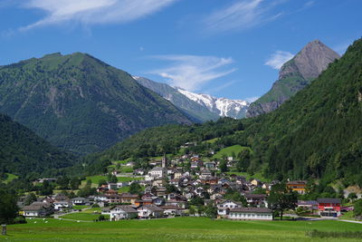 Scenic view of townscape by mountains against sky