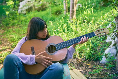 Full length of woman playing guitar