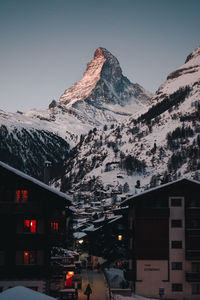 Snow covered houses and mountains against sky