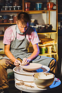 Potter making pot while sitting in pottery workshop