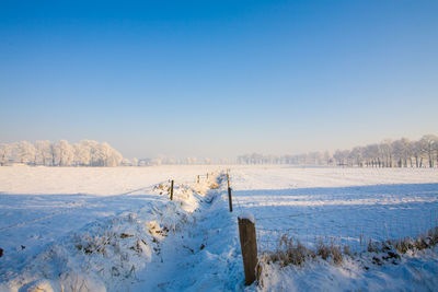 Scenic view of snowy field against clear sky during winter
