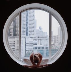 Full length of woman practicing yoga at circular window