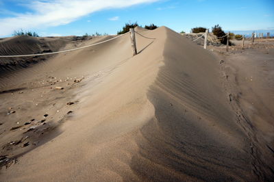 Sand dunes at beach against sky