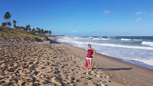 Rear view of woman walking on beach against clear sky