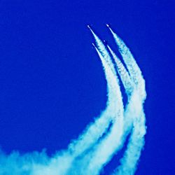 Low angle view of airplane flying against clear blue sky