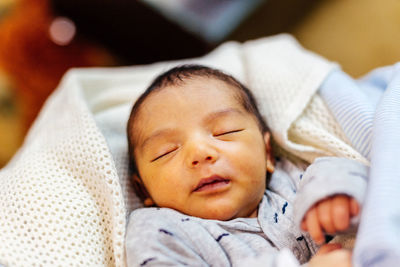 Close-up of baby sleeping on bed at home