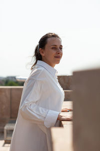 Young woman standing against railing