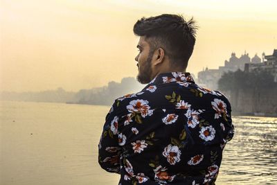 Man standing by sea against sky during sunset