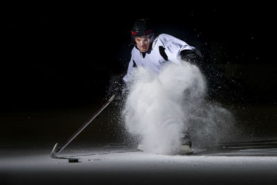 Man playing ice hockey against black background