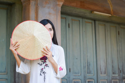 Full length portrait of woman standing against wall
