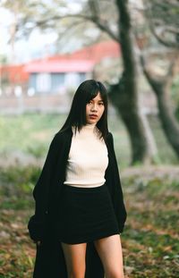 Young woman standing against trees