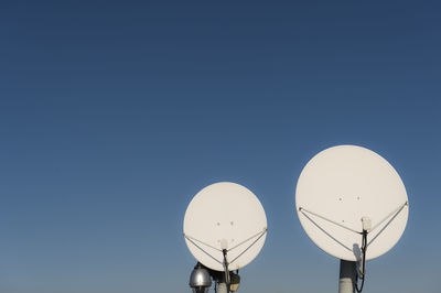 Low angle view of communications tower against clear blue sky