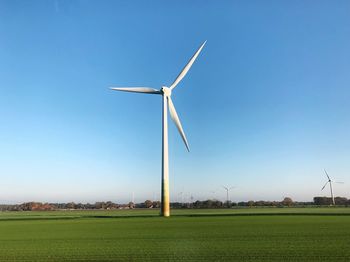 Windmill on field against clear sky