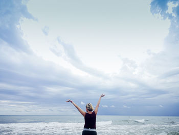 Rear view of woman standing in sea against sky