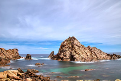 Rock formation on beach against sky