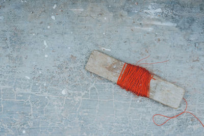 High angle view of red thread wrapped in wood